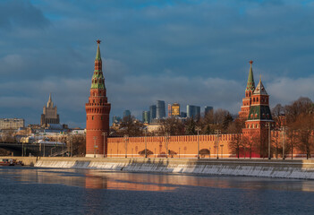 Obraz premium Vodovzvodnaya, Blagoveshchenskaya and Borovitskaya towers on the Kremlin embankment of the Moskva River and the Moscow City Business Center in the background on a sunny winter day, Moscow, Russia