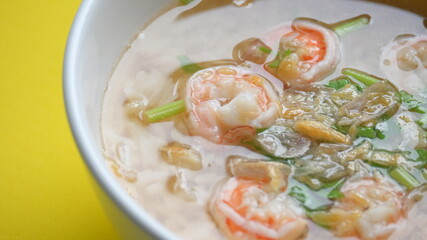 rice soup with shrimp in white bowl on yellow background