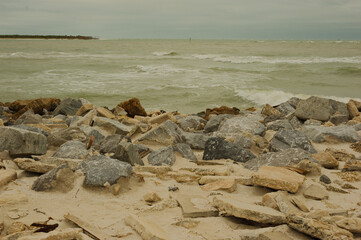 Low View out over large rocks at St. Pete Beach, Florida, Large white cap waves splashing up on and over large rocks. Towards Shell Key. On a cloudy day. Room for copy.
