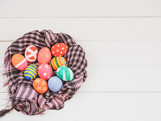 Painted easter eggs in the egg tray on  wood plank table and background.