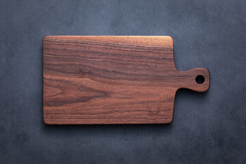 Black walnut handmade wooden chopping board. Handmade black walnut wooden cutting board on dark tone texture background.	