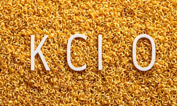 Yellow grain texture, chemical formula KClO, white text overlay, golden particles, macro photography, scientific background, crystalline structure, potassium chlorate, oxidizing agent