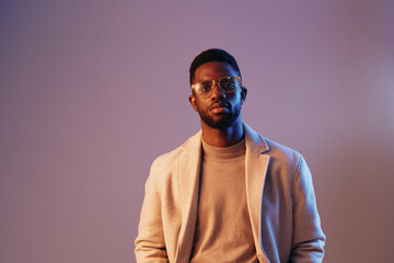 Obraz premium Stylish African American man in a beige coat, conveying confidence and sophistication against a soft purple background Modern fashion and emotions captured perfectly