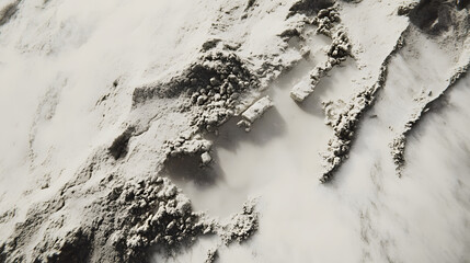 High-angle close-up shot of a textured, gray and white powder substance.  The powder forms intriguing patterns and shapes, resembling a miniature landscape. The texture is coarse and uneven.