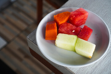 Fresh fruit slices on a white plate for breakfast. Watermelon, melons and papaya slices on the table. 