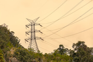 Photograph of a large electricity Transmission Tower on a grassy hill against an orange sunset sky...