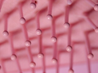 A close up of a pink brush with many small pink balls on it