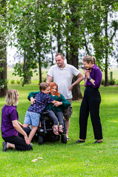 Boy and parents chatting with occupational therapist and speech pathologist outdoors