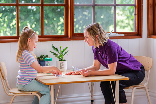 Child with speech disability looking at sound cards talking with speech-language pathologist