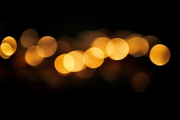A blurred bokeh light effect with soft glowing circles in various sizes, shimmering in golden hues against a black background