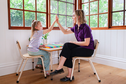 Speech therapist professional with child in clinic high five together to celebrate success