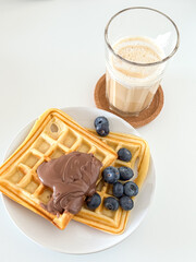 Delicious waffles with chocolate spread and blueberries with a glass of coffee