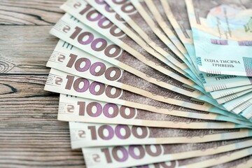 Big amount of ukrainian new one hundred hryvnia money bills with modern design on wooden background. Financial concept, business