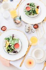 Elegant table setting with salad, orange juice, and silverware.