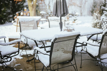 Snow-covered patio furniture and table in backyard in winter