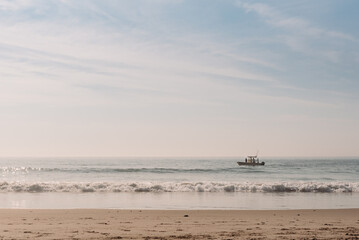 Small boat floating on a calm ocean under a clear, bright sky.