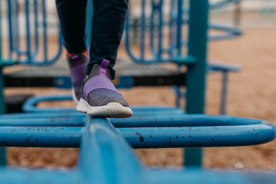 Child balancing on blue playground equipment in an outdoor park.