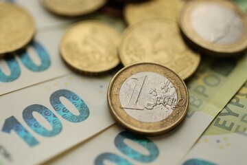 Big amount of euro cent coins lies on hundred euro bills banknotes