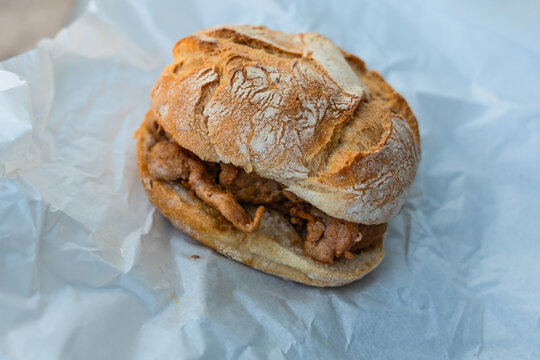 Portuguese traditional Lisbon street or bar food Bifana sandwich, thinly pounded pork strips that have been marinated in a white wine, garlic, paprika, vinegar, with piri piri on crispy bread 