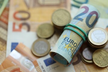 Roll of euro currency money bills and many euro cents on banknotes of european union