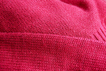 A red sweater knitted in stocking stitch: the front and back of the garment in close-up. A fabric created using the stockinette stitch technique and a fabric with a purl stitch lying next to it.