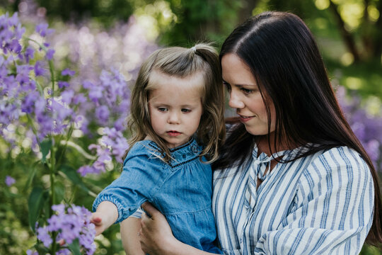 Mother and daughter stand together in field of wildflowers