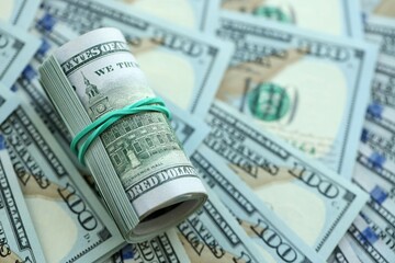 Roll of hundred dollar bills USD banknotes lies on big amount of united states money