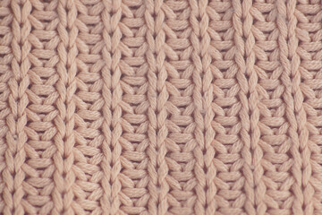 An example of the work of an experienced craftsman: a light pink sweater fabric laid out evenly on a surface with neatly knitted vertical rows using the English (fisherman's) rib technique.