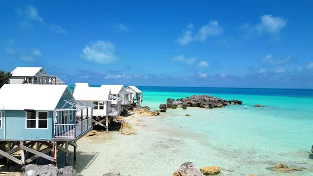 Drone footage of coastal wooden bungalows near Daniel's Head Beach Park on a sunny day, Bermuda