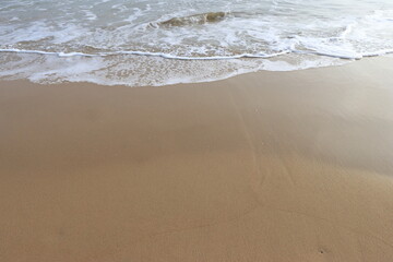 waves crashing on shore of sandy beach on a cloudy day