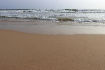 waves crashing on shore of sandy beach on a cloudy day