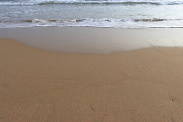 waves crashing on shore of sandy beach on a cloudy day