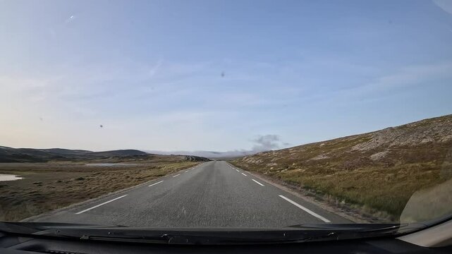 Driving along Norway's E69 road in the north. Surrounded by stunning, rugged landscapes with rocks, grass, moss, lichens, and small lakes creating a wild and natural atmosphere.
