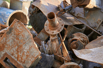A large and rusty industrial scrap metal pile stacked high with discarded materials and debris. Closeup view showcasing a messy pile of rusted, neglected industrial scrap metal in an outdoor setting