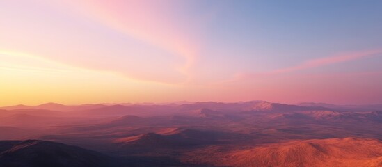 Fototapeta premium Soft-focus sunset over vast, hazy mountain range.