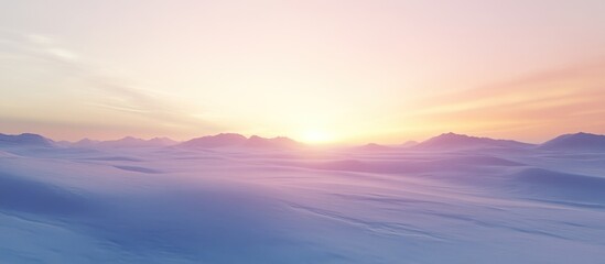 Fototapeta premium Serene sunset over a misty, snow-covered mountain range.