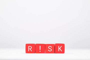 Red blocks spelling the word 'RISK' on a plain background symbolize caution and assessment in decision-making.