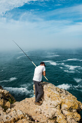 Solitary Fisherman Casting Line into Ocean from Algarve Coast