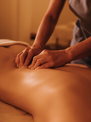 Hands of female chiropractor massaging shoulders of young woman lying on massage table. Concept of physical therapy treatment, neck pressure point. Soft focus, blurred, noise effect