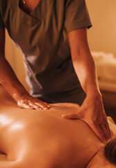 Hands of female chiropractor massaging shoulders of young woman lying on massage table. Concept of physical therapy treatment, neck pressure point. Soft focus, blurred, noise effect