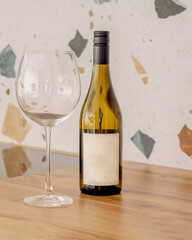 A bottle of white dry wine next to a glass