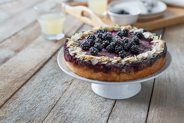 Fruit cake with blackberries and almonds on cake stand; whole gluten-free dessert ready to eat
