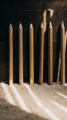 Collection of oversized colored pencils lined against a wooden wall in natural light