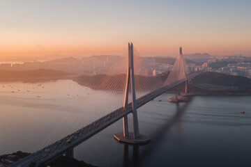 Obraz premium Transport bridge connecting two cities over water at sunset with a skyline in the background