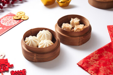 Steamed bao buns and dimsum in a traditional bamboo steamer on a white plain background.