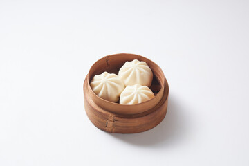 Steamed bao buns in a traditional bamboo steamer on a white plain background.