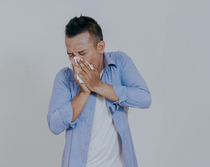 Asian man cover his nose and mouth with tissue when sneezing, isolated on white background.