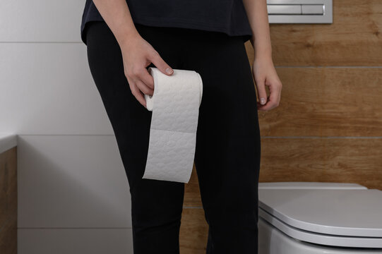 Kobieta trzymająca rolkę papieru toaletowego w łazience, problemy żołądkowe 
