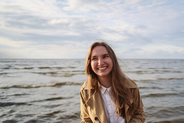 pretty girl walking on a beach in beige trench coat