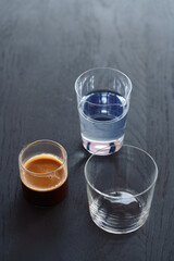 Ingredients for espresso tonic with clear ice cube in tumbler glass on oak wood table with copy space